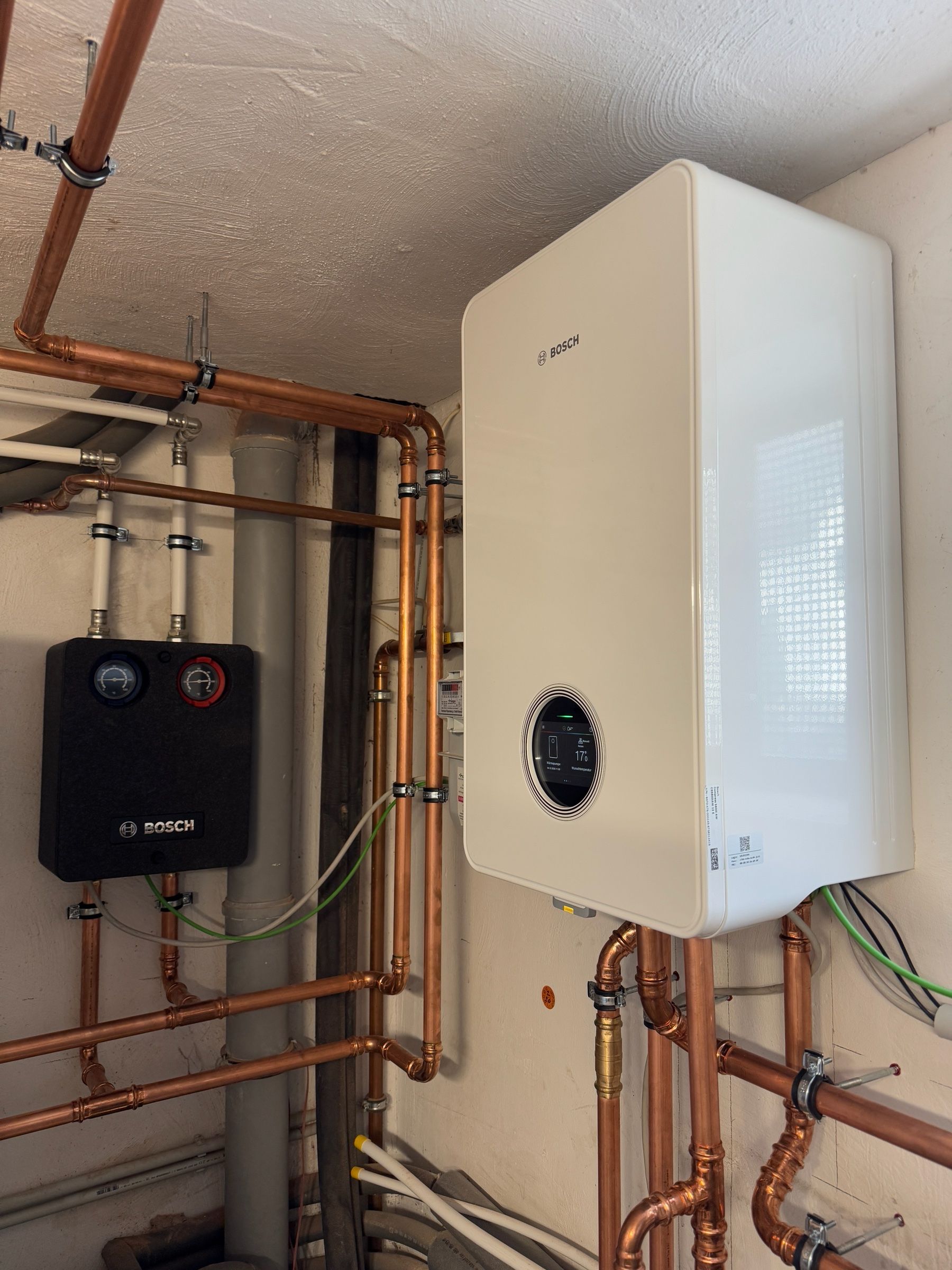 Wandhängende Inneneinheit einer Wärmepumpe mit Kupferleitungen in einem Technikraum