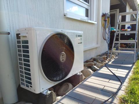 Bosch-Außengerät einer Klimaanlage auf Kieselsteinen entlang eines Hauswegs