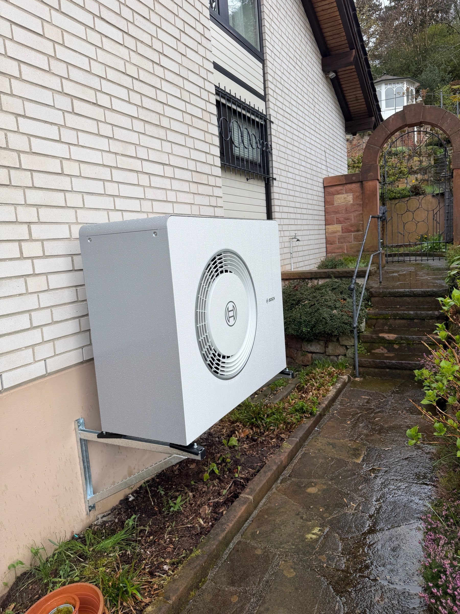 Außeneinheit einer Bosch-Wärmepumpe auf einer Wandkonsole an einer Klinkerwand