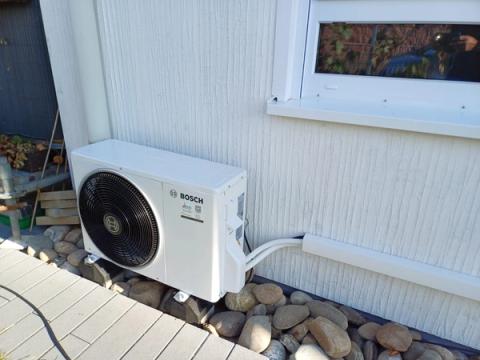 Bosch-Außengerät einer Klimaanlage auf Kieselsteinen an einer weißen Hauswand