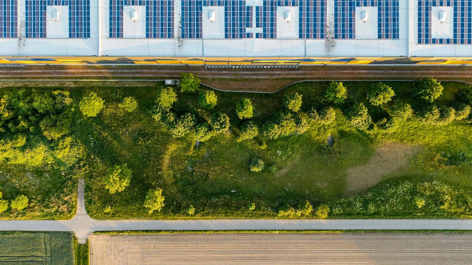 Vue aérienne d'une grande toiture industrielle entièrement équipée de panneaux photovoltaïques en France, entourée de champs agricoles