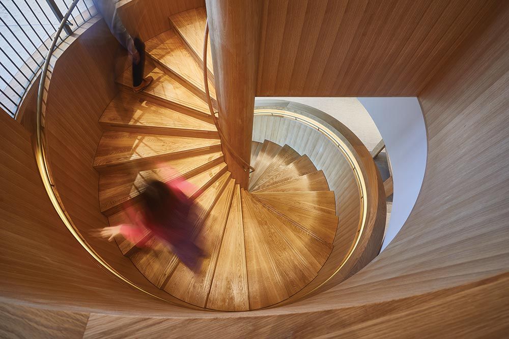 Overhead view of a wooden spiral staircase with a person walking up it