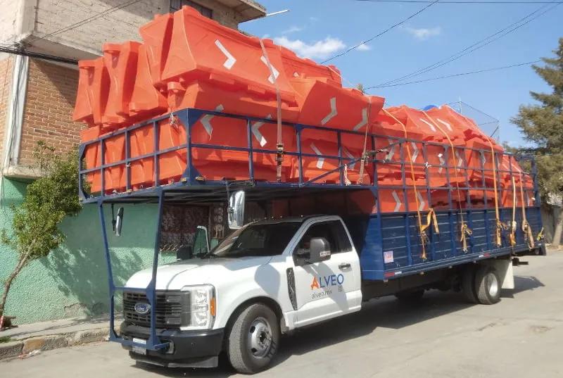 Camioneta de Alveo cargada con Barrera Ray naranja apilada, lista para entregar en obra