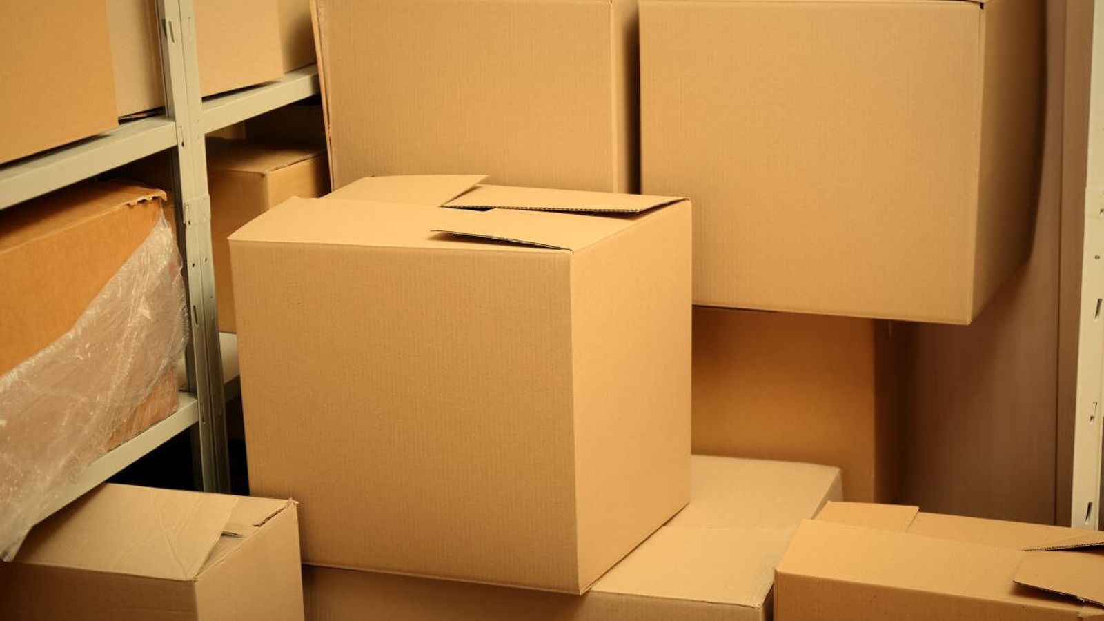 Cajas de cartón kraft cerradas y apiladas en una bodega con estantería metálica