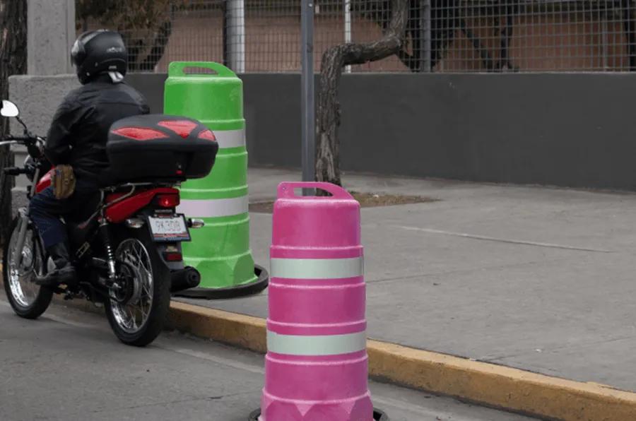 Trafitambos verde y rosa con bandas reflejantes junto a la banqueta, al lado de un motociclista detenido