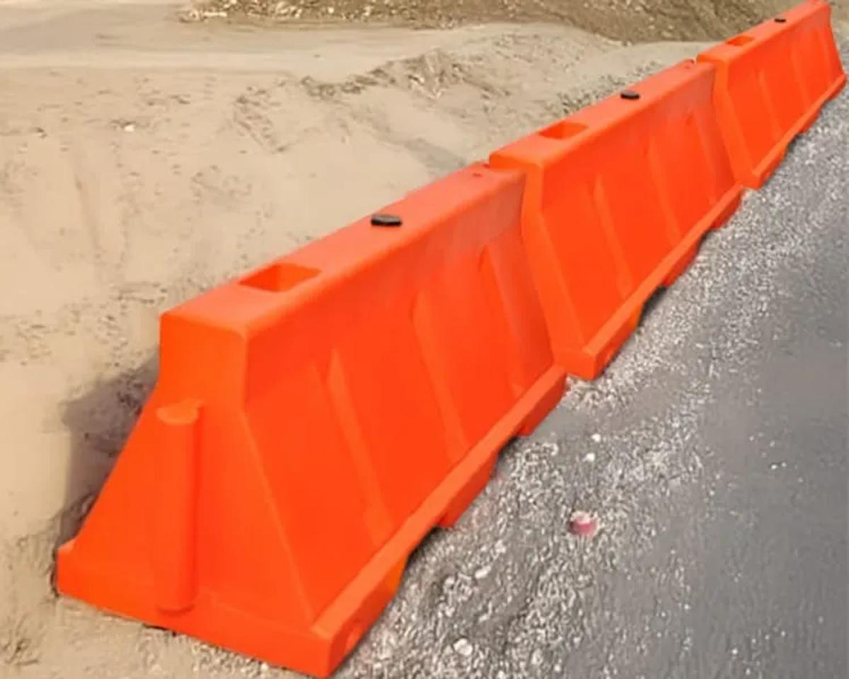 Fila de barreras de plástico naranja delimitando el borde de una carretera en obra