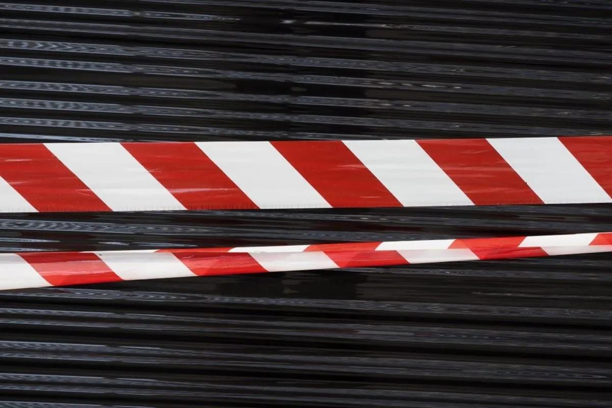 Dos cintas de peligro rojas y blancas frente a una cortina metálica negra