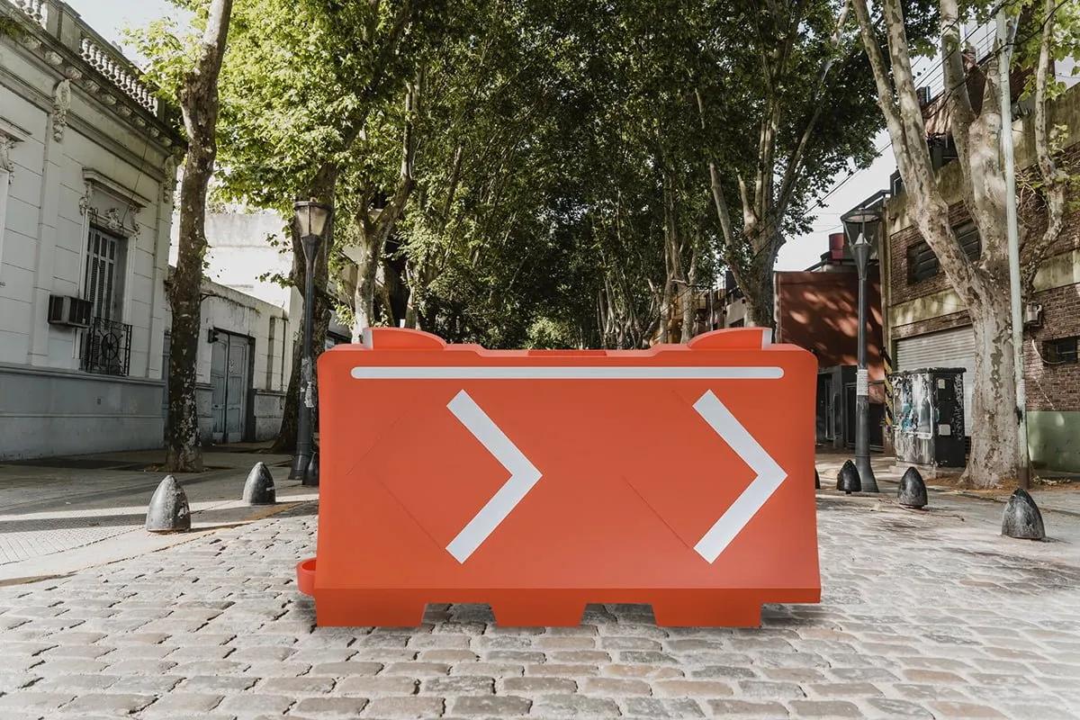 Barrera Ray naranja con dos flechas reflejantes sobre una calle empedrada con árboles, render