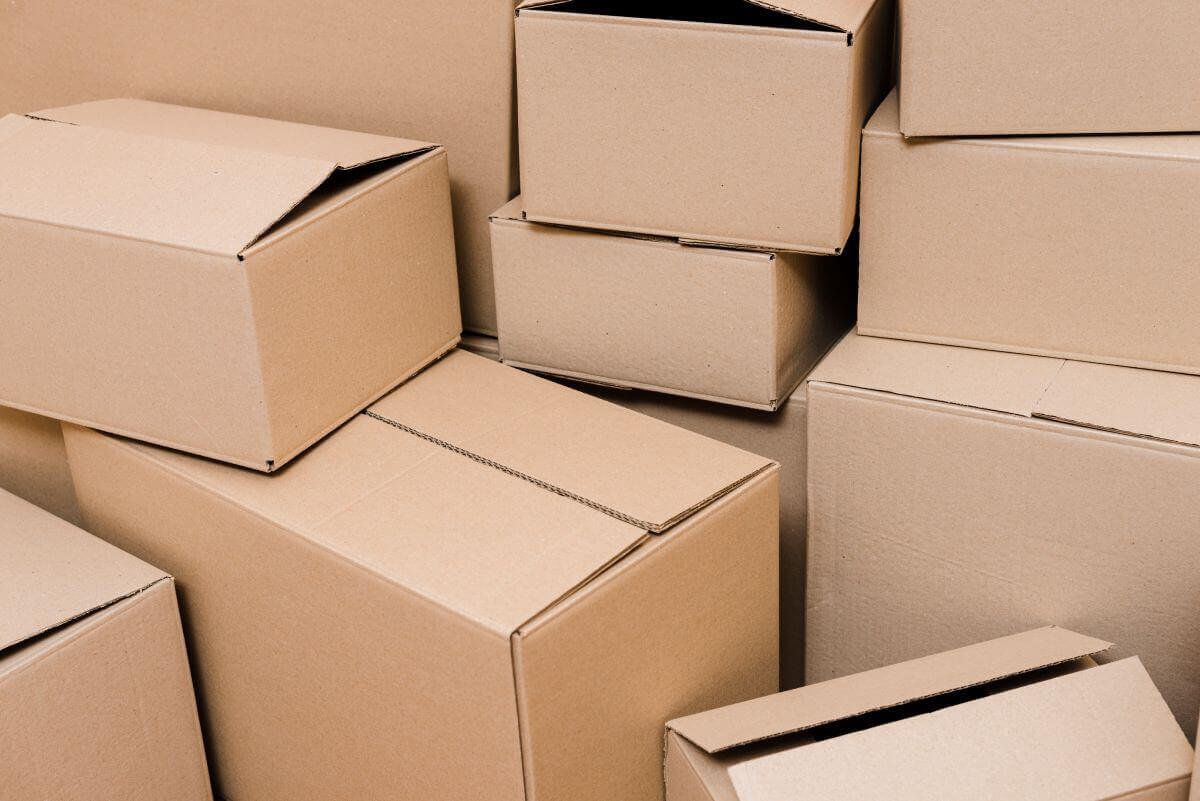 Cajas de cartón de distintos tamaños apiladas sin orden, varias con las solapas abiertas