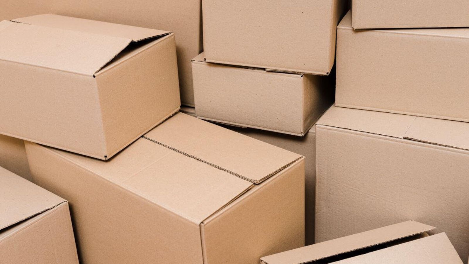 Cajas de cartón de distintos tamaños apiladas sin orden, varias con las solapas abiertas