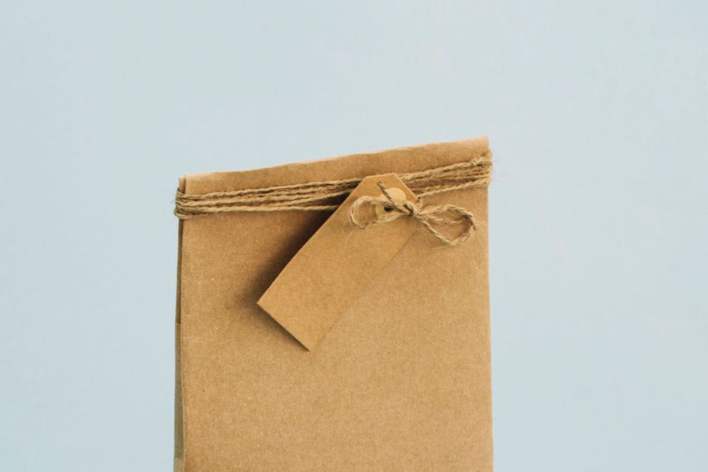 Bolsa de papel kraft cerrada con hilo de yute y una etiqueta kraft sobre fondo azul claro