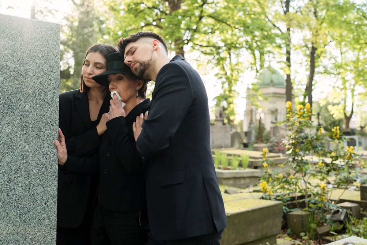 tres personas vestidas de negro en cementerio