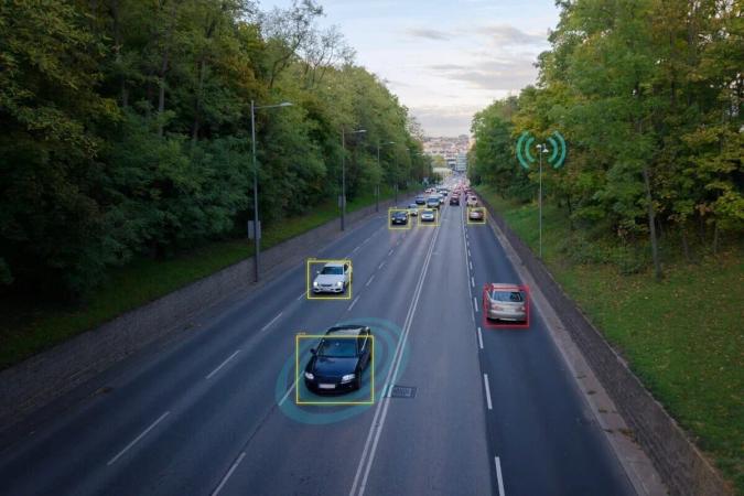 Autopista arbolada con autos marcados por recuadros de un sistema de detección de tráfico