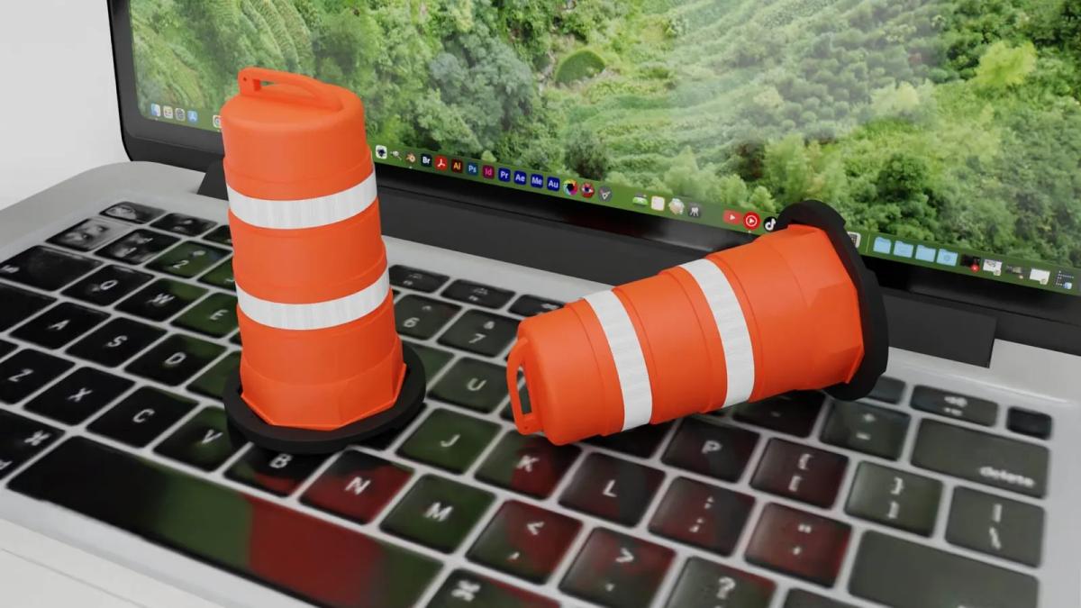 Render de dos trafitambos naranjas en miniatura con bandas reflejantes sobre el teclado de una laptop