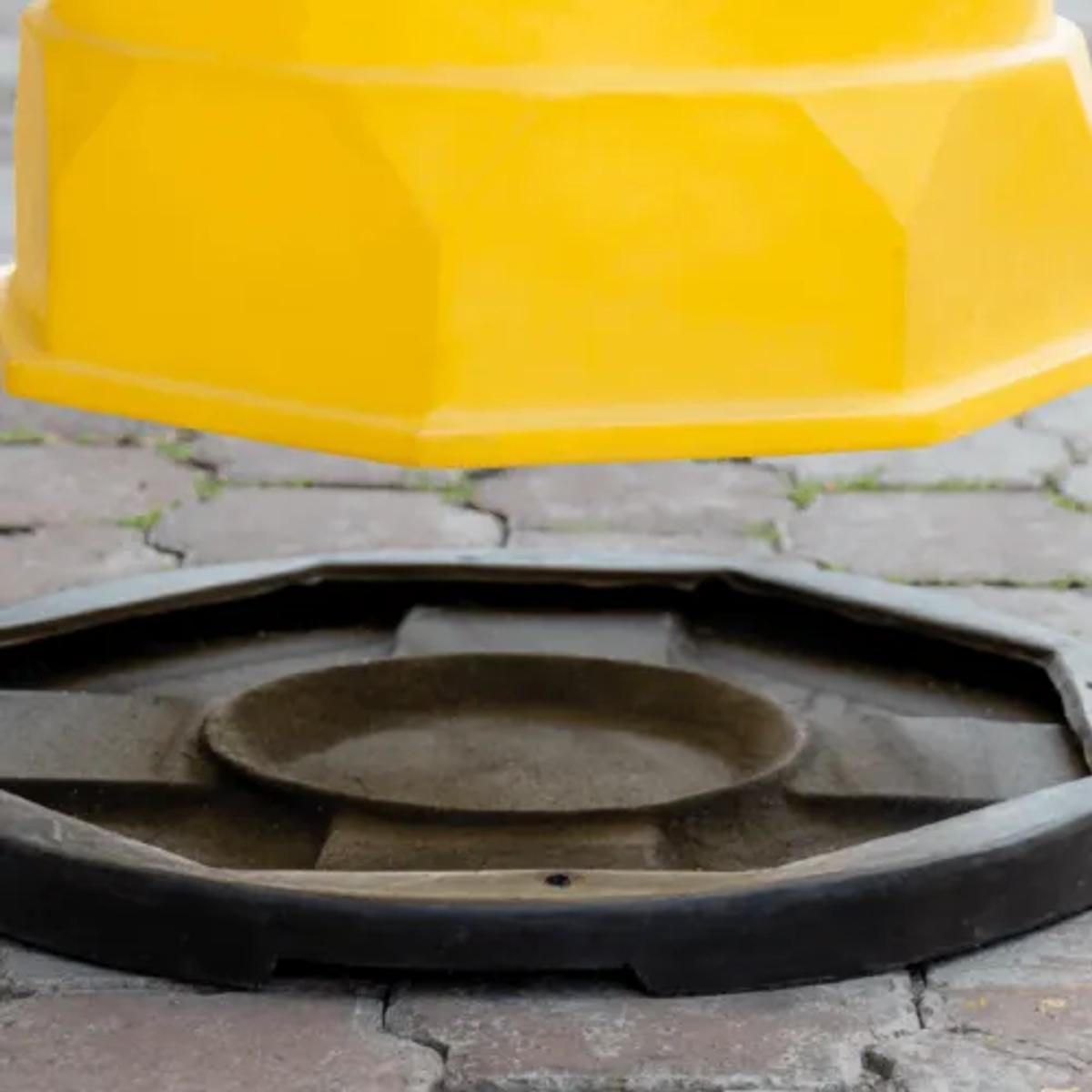 Trafitambo amarillo a punto de colocarse sobre su base negra en un piso de adoquín