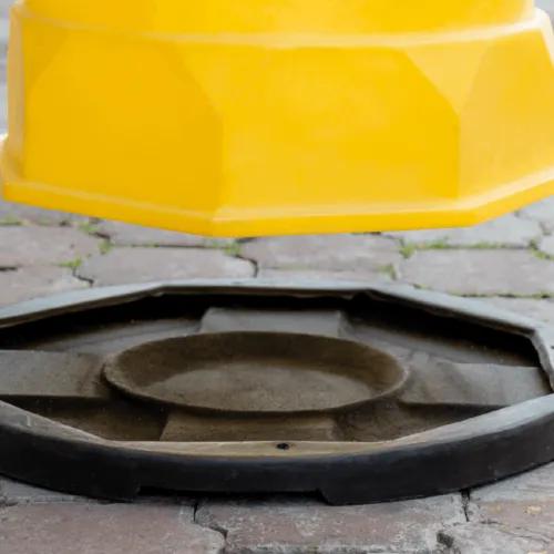 Trafitambo amarillo a punto de colocarse sobre su base negra en un piso de adoquín
