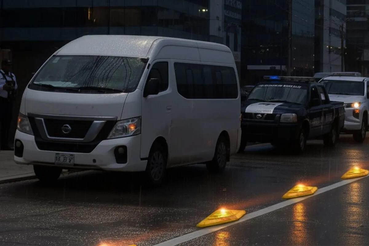 Canalizadores con luz ámbar encendida en el borde de un carril, junto a una camioneta y una patrulla en una calle mojada