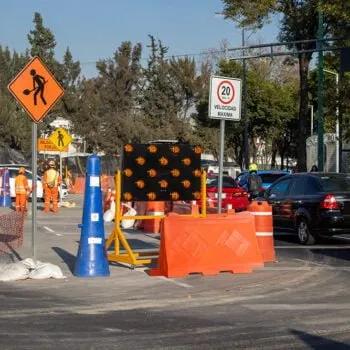 Barrera Ray naranja en una obra de la CDMX junto a un cono azul, tablero de flechas y señales de obra