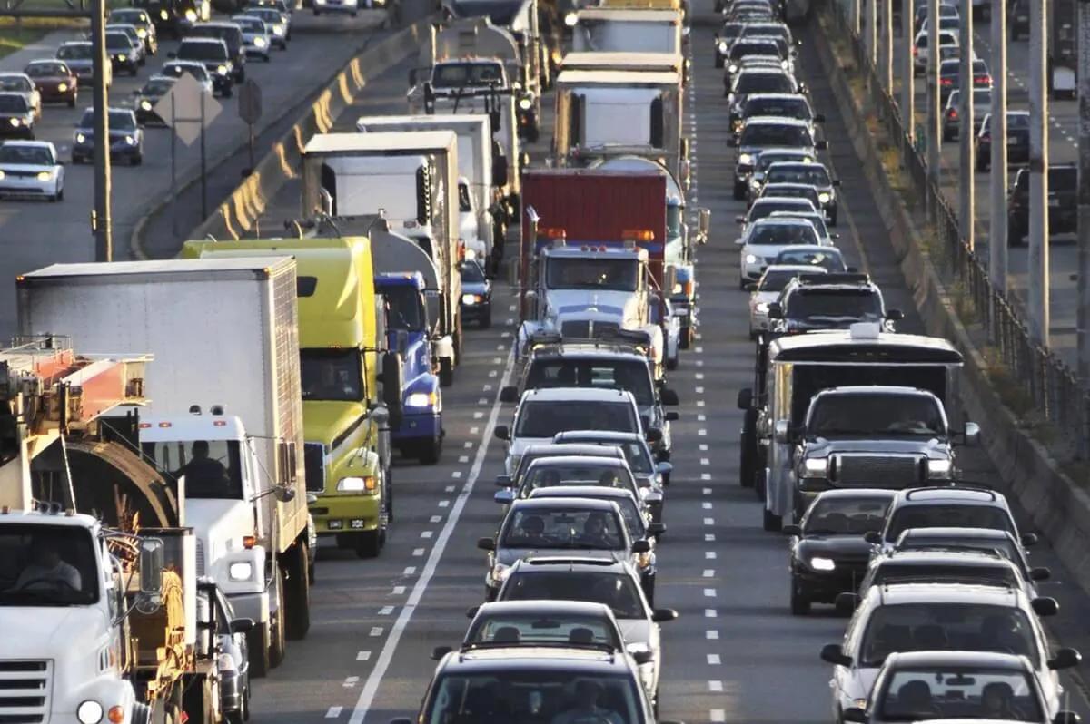 Embotellamiento de autos y camiones de carga en una vía rápida de varios carriles