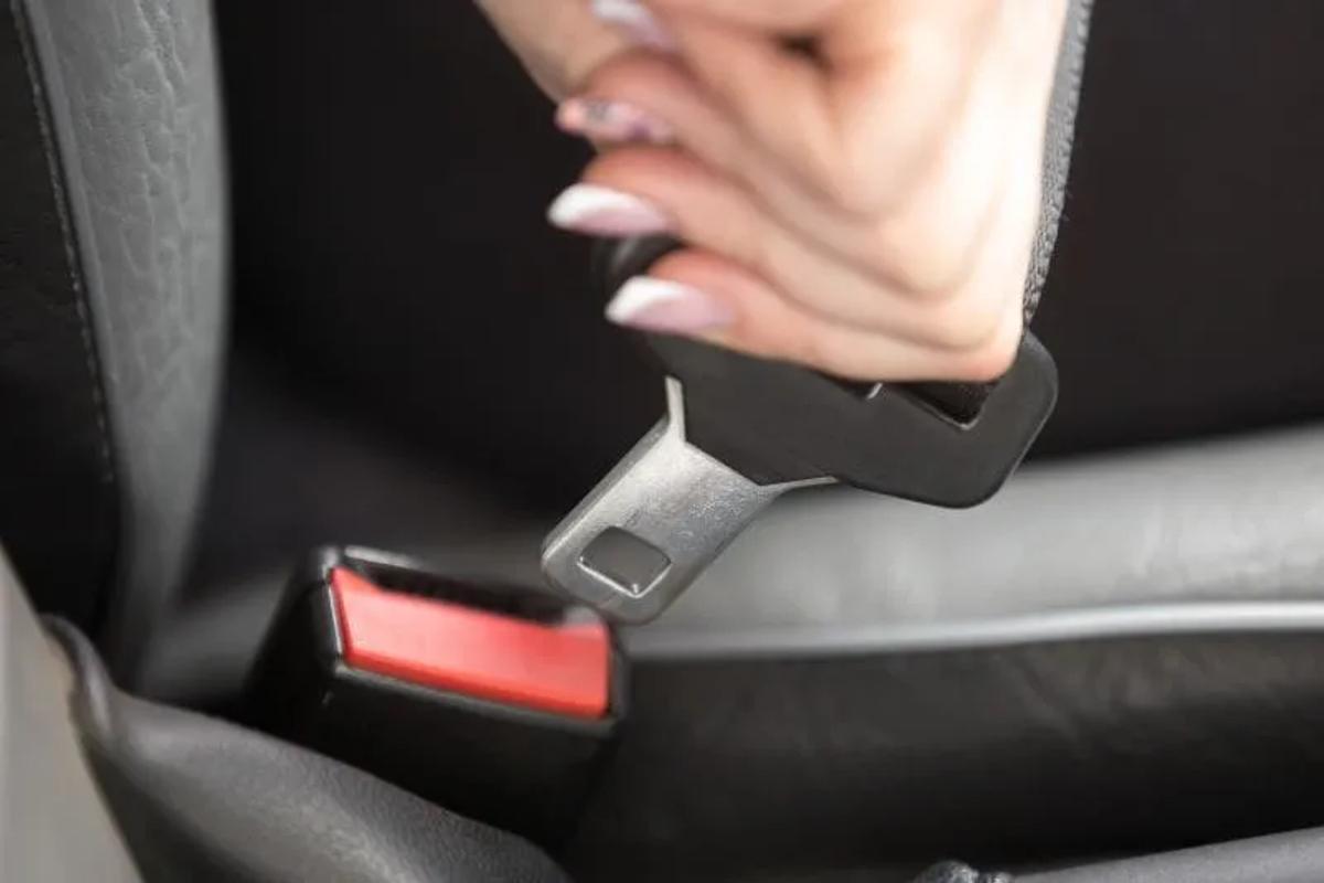 Mano abrochando el cinturón de seguridad en el asiento de un auto