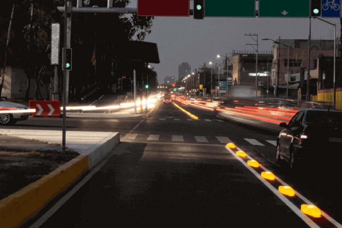 Canalizadores con luz encendidos de noche a lo largo de la línea que separa un carril exclusivo en una avenida