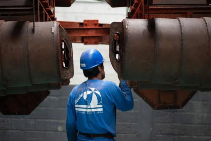 Trabajador con casco azul, de espaldas, entre grandes moldes metálicos en una planta de fabricación