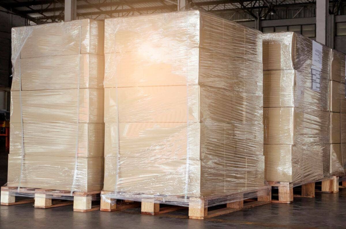 Tarimas de madera con cajas de cartón apiladas y envueltas con playo en un almacén