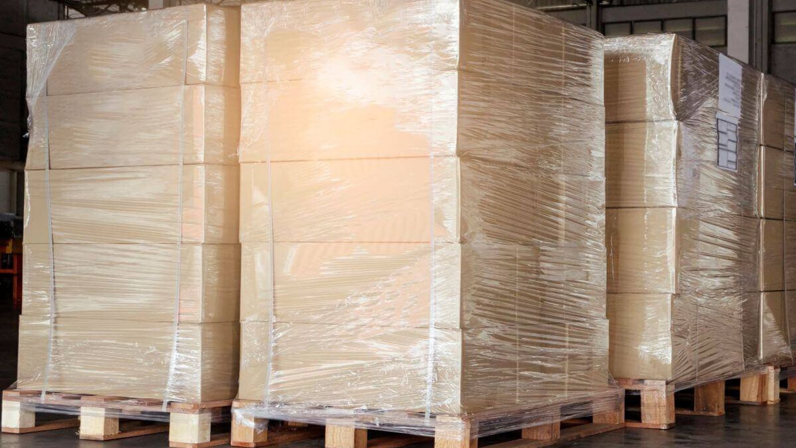 Tarimas de madera con cajas de cartón apiladas y envueltas con playo en un almacén