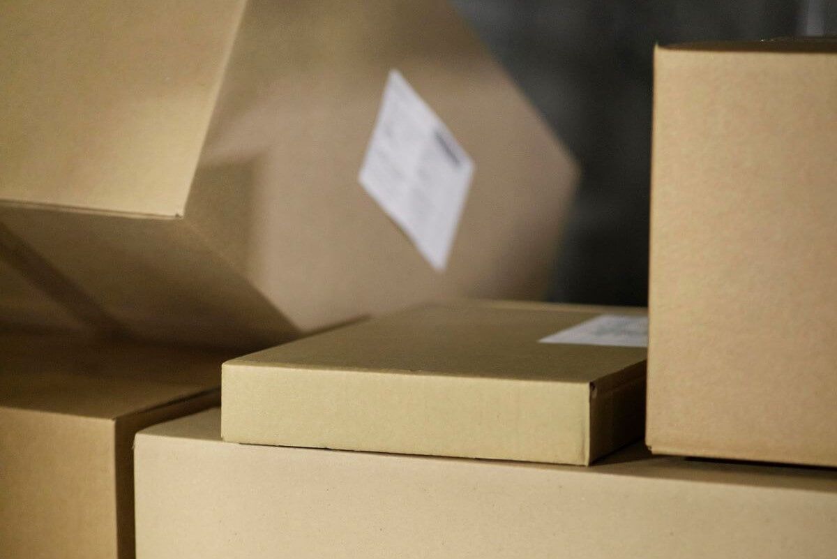 Cajas de cartón corrugado kraft apiladas con etiquetas de envío blancas en un almacén
