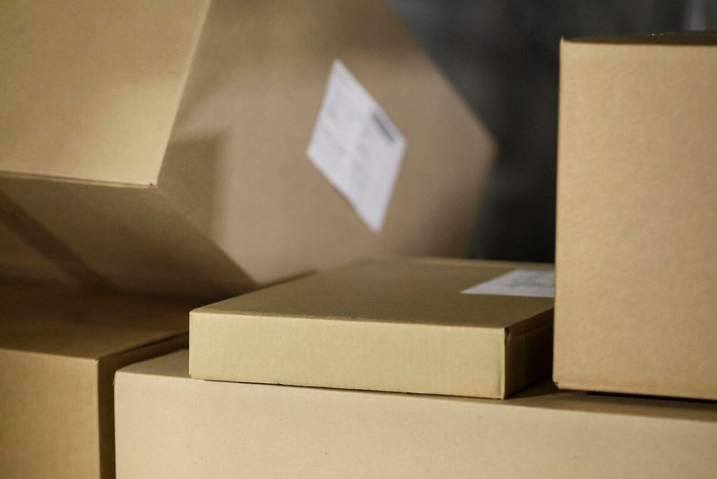 Cajas de cartón de distintos tamaños con etiquetas blancas; una plana tipo mensajería descansa sobre una caja grande