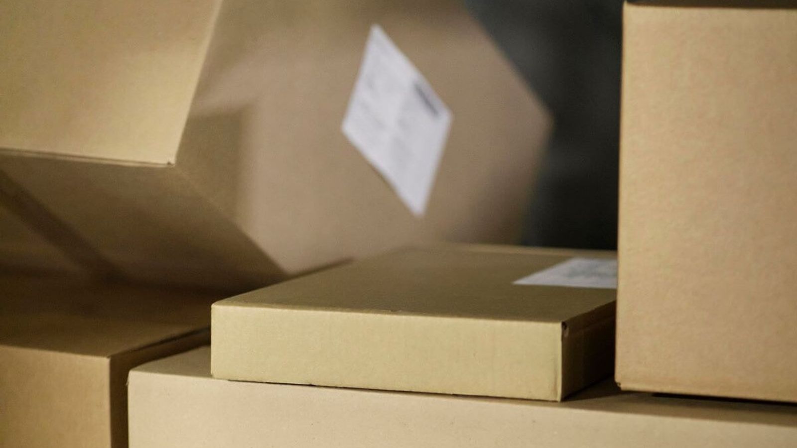 Cajas de cartón corrugado kraft apiladas con etiquetas de envío blancas en un almacén