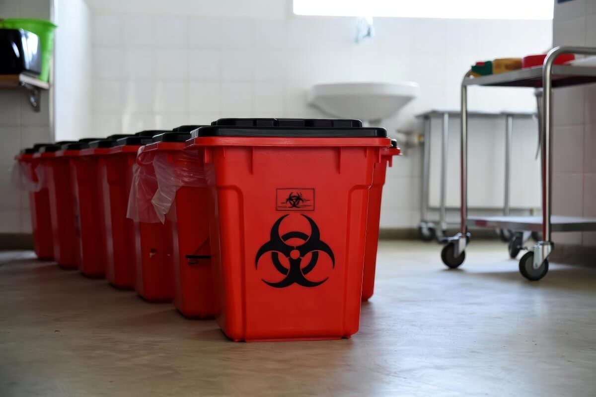 Contenedores rojos de residuos peligrosos biológicos alineados en instalación médica