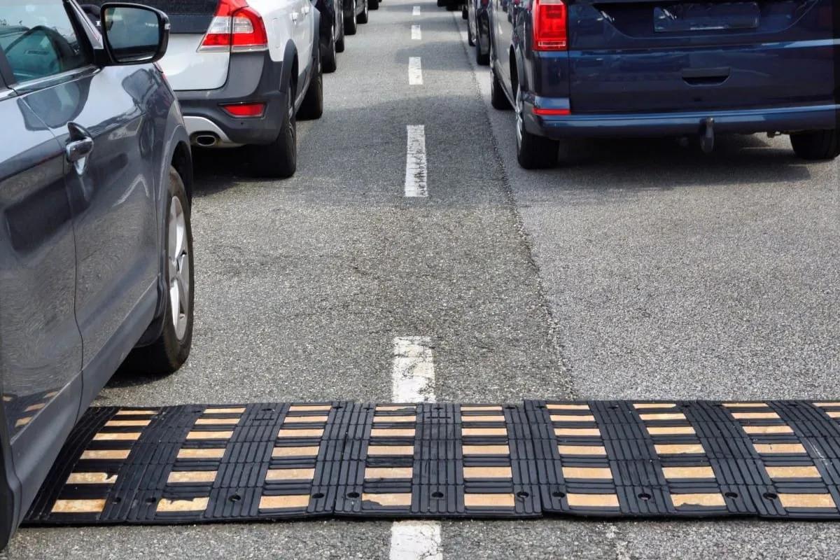 Reductor de velocidad modular de hule negro con franjas amarillas cruzando un carril entre autos detenidos
