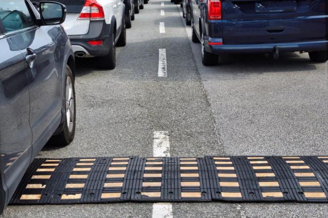 Reductor de velocidad modular de hule negro con franjas amarillas cruzando un carril entre autos detenidos
