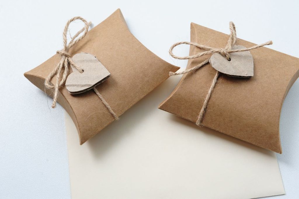 Dos cajitas tipo almohada de cartón kraft atadas con cordón de yute y etiqueta de corazón