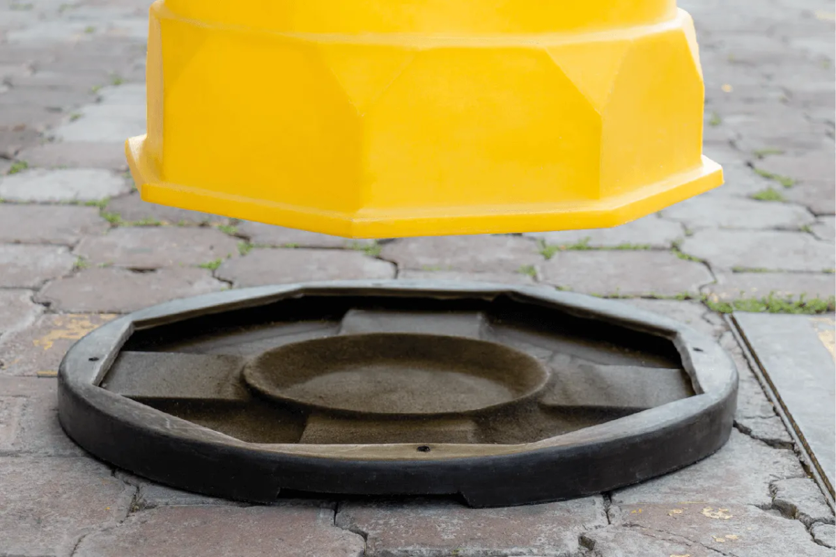 Trafitambo amarillo de fondo octagonal a punto de montarse sobre una base negra redonda en un piso de adoquín
