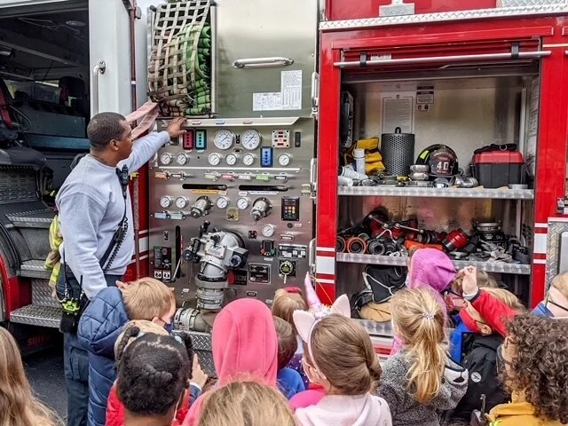 Day School Student exploring fire truck with fireman on a visit