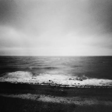 Unruhiges Meer. Eine stürmische See mit beeindruckenden Wellen, die gegen das Ufer schlagen. Der dunkle Himmel trägt zur turbulenten Atmosphäre bei.