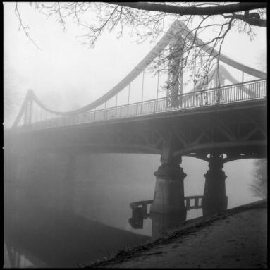 Foggy scene with a river and bridge.