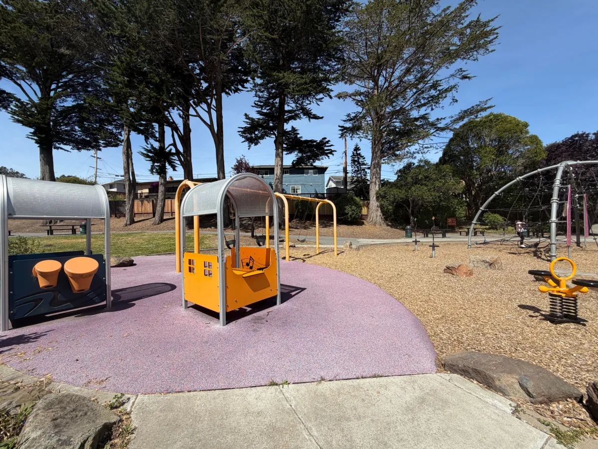 Musical corners with drums and playarea, ride on toys, and swings and spinners in back