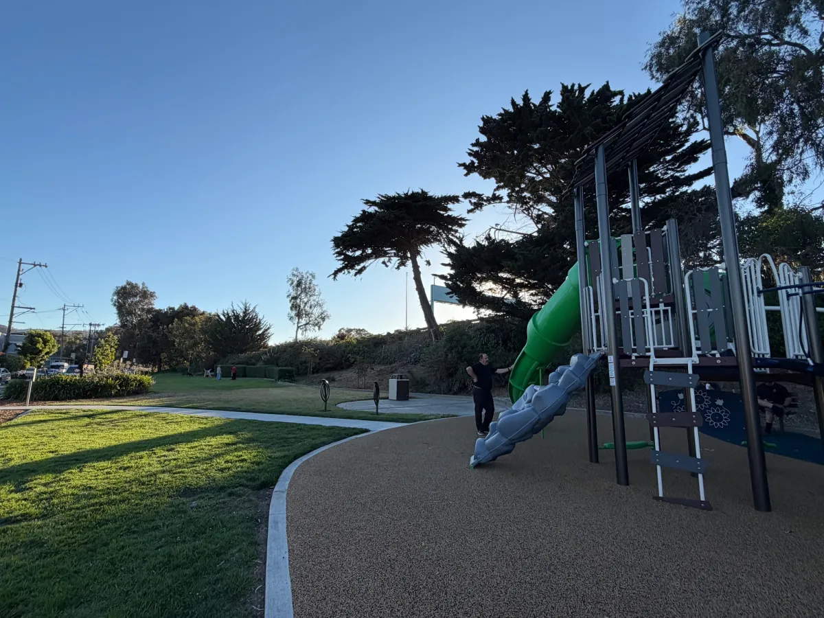 Long, narrow grassy field to either side of the playground