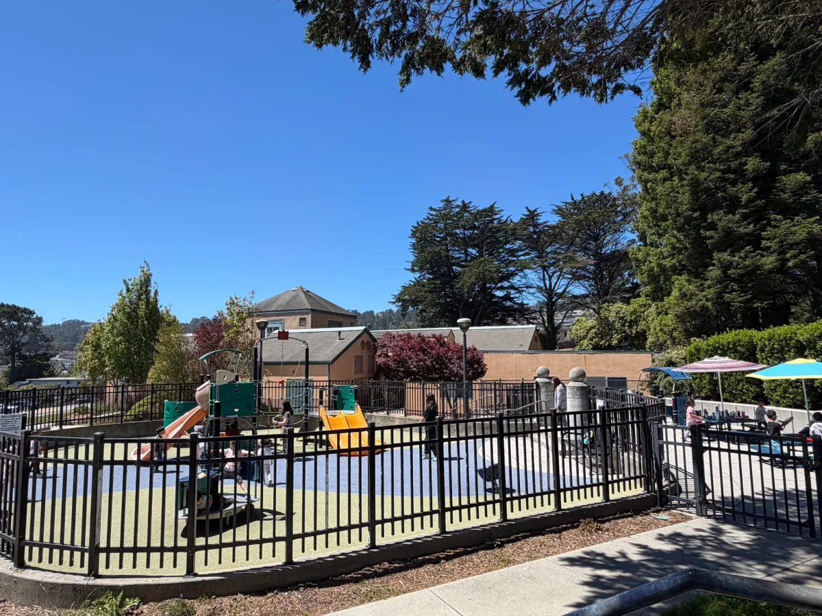Fully enclosed toddler zone with nearby picnic tables having clear sightlines