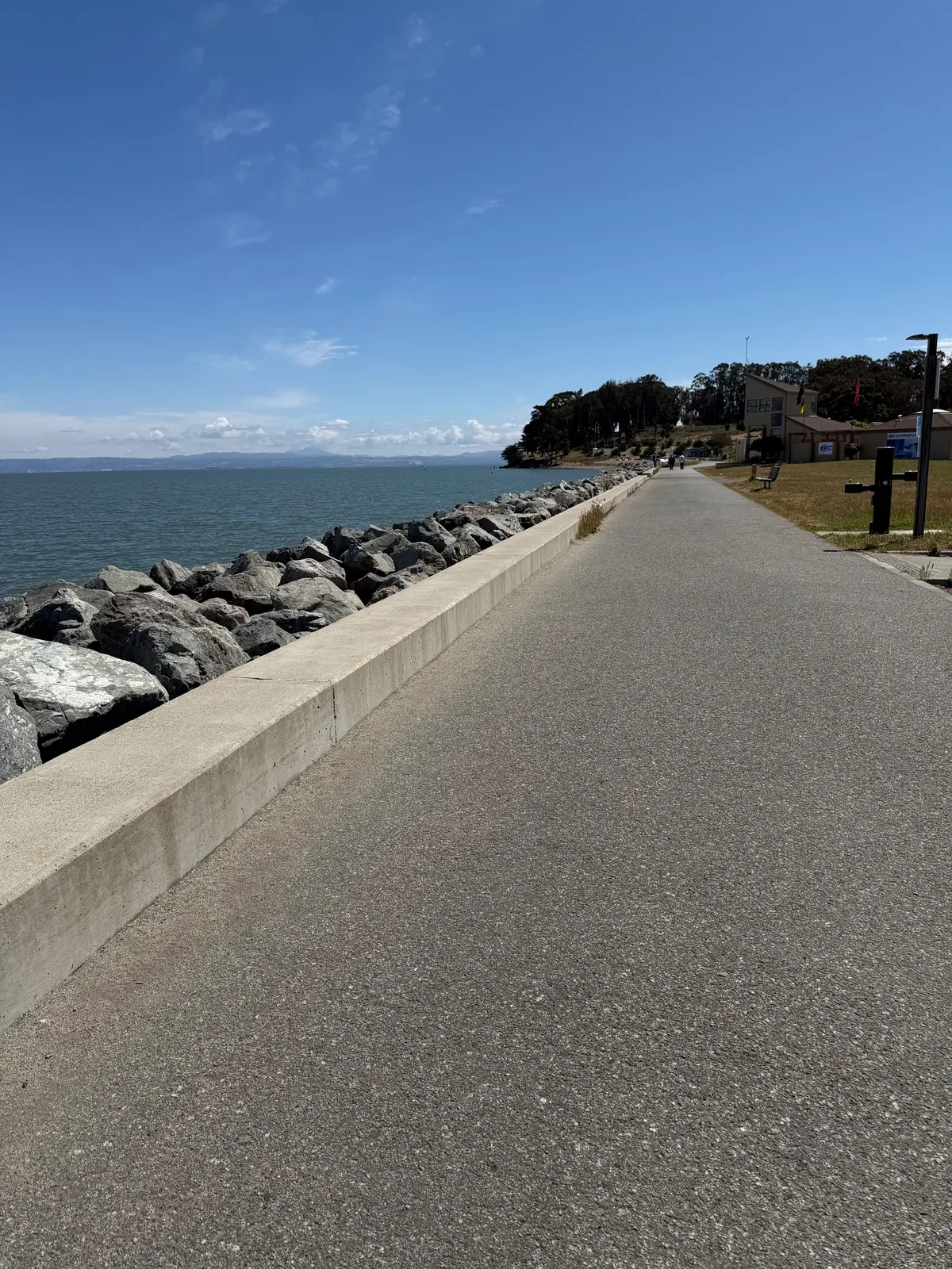 Walkway along coyote point beach with view of the san mateo bridge and planes flying by