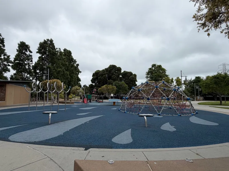 Playground overview with climbing structure, spinners, and play gym in back