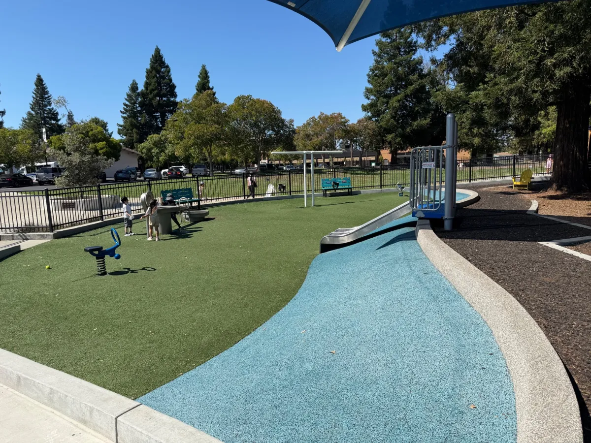 Toddler play area with water table, baby swings, slides, and ride on toys