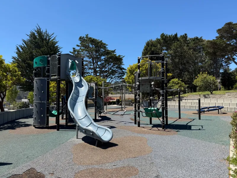 Big kid structure features slide, rock climbing wall, rope bridges, hammocks, and carousel