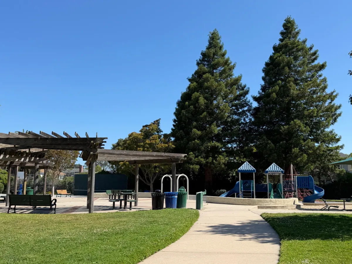 Large pergola provides shaded seating in front of playground