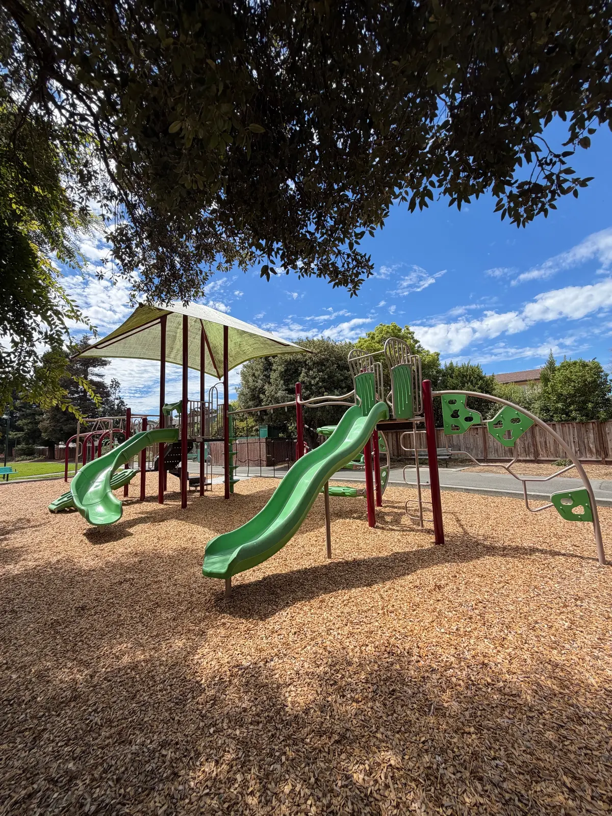 Big kid play structure consists of 2 slides, climbing areas, monkey bars, and large shade covers