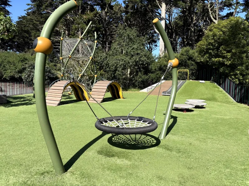 Flat netted swing, mounded structures, and stepping platforms in the background.