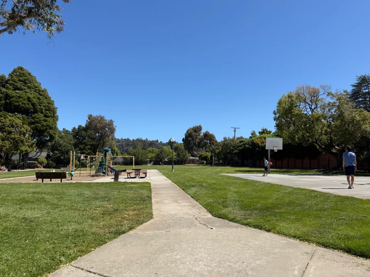 Basketball court on the right, playground on the left with just 1 picnic table